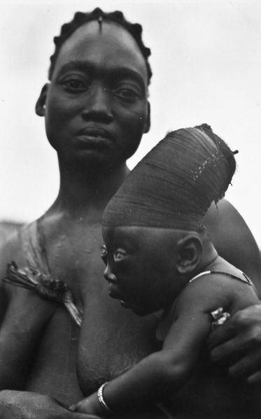 Tener una parte trasera de la cabeza alargada era uno de los ideales de belleza femenina de la etnia Mangbetu.  Esta formación del cráneo se logró volviendo firmemente las cabezas de los bebés desde su nacimiento.